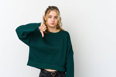 Beyaz arka plandaki genç beyaz kadın hoşlanmadığı bir hareket sergiliyor, başparmakları aşağıda. Anlaşmazlık konsepti.