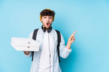 Elinde pizza tutan genç Arap öğrenci yan tarafı işaret ediyor.