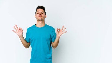 Beyaz arka planda izole edilmiş genç beyaz adam yoğun bir günün ardından rahatlıyor. Yoga yapıyor..