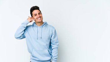 Beyaz arka planda izole edilmiş genç beyaz bir adam parmakları olan bir cep telefonu hareketi gösteriyor..