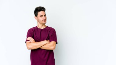 Beyaz arka planda izole edilmiş genç beyaz adam alaycı bir ifadeyle kameraya bakıyor..