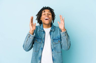 Kot ceket giyen genç siyahi adam elini göğsünde tutarak kahkaha atıyor..