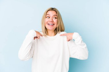 Sarışın, beyaz tenli, izole bir kadın. Parmakla işaret ederek şaşırmış, gülümseyerek..