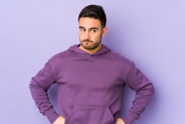 Mor arka planda soyutlanmış, kafası karışmış, şüpheli ve kararsız genç bir beyaz adam..