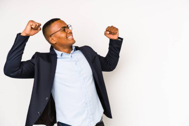 Genç iş adamı beyaz arka planda izole edilmiş zafer sonrası yumruğunu kaldıran, kazanan konsept.