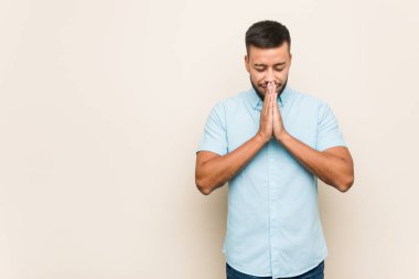 Güney Asyalı genç adam, el ele tutuşup, ağzının kenarında dua ediyor, kendinden emin..