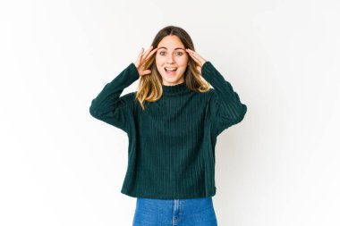 Beyaz arka planda izole genç beyaz kadın hoş bir sürpriz alıyor, heyecanlı ve el kaldırıyor..