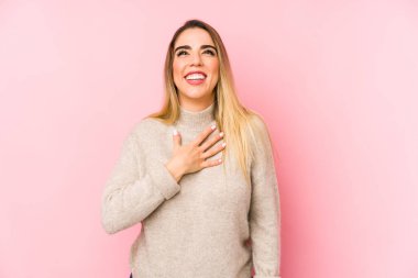 Orta yaşlı bir kadın soyutlanmış bir geçmişle gülüyor ve elini göğsüne koyuyor..