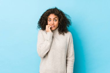 Genç Afro-Amerikan kıvırcık saçlı kadın tırnaklarını yiyor, gergin ve çok endişeli..