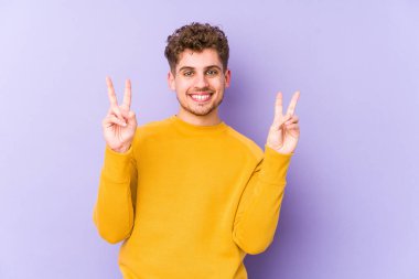 Sarışın, kıvırcık saçlı, beyaz, neşeli ve tasasız bir adam parmaklarıyla barış sembolü gösteriyor..