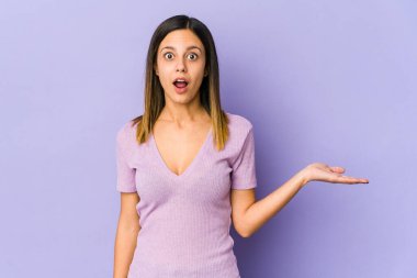 Mor arka planda izole edilmiş genç bir kadın, avuç içinde kopya alanı tutmaktan etkilenmiş..