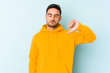 Mavi arka planda izole edilmiş genç beyaz bir adam hoşlanmadığı bir jest yapıyor. Anlaşmazlık konsepti.