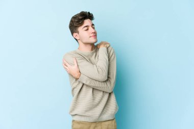 Kafkasyalı genç adam mavi arka planda izole edilmiş, güler yüzlü ve mutlu..