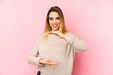 Soyutlanmış arka planda orta yaşlı bir kadın iki eliyle bir şey tutuyor, ürün sunumu..