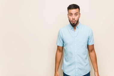 Genç Güney Asyalı adam omuz silker ve gözleri açık kalır..