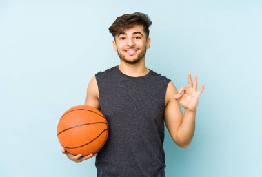 Basketbol oynayan genç bir Arap adam neşeli ve kendinden emin bir şekilde iyi niyet gösteriyor..