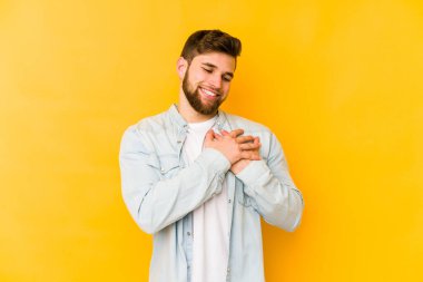Sarı arka planda izole edilmiş beyaz bir genç, dost canlısı bir ifadeye sahip, avuçlarını göğsüne bastırıyor. Aşk konsepti.