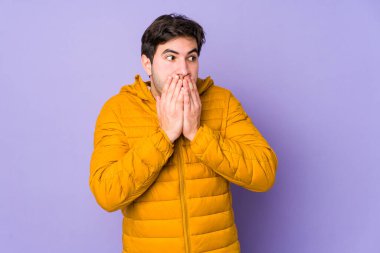 Mor arka planda izole edilmiş genç bir adam. Düşünceli bir şekilde bir fotokopi odasına bakıyor. Ağzı elle kapatıyor..