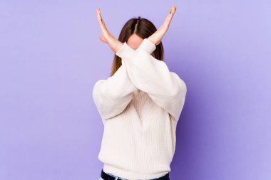 Mor arka planda izole genç beyaz kadın iki kolu çapraz tutuyor, inkar kavramı.