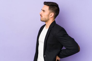 Mor arka planda izole edilmiş beyaz bir adam sırt ağrısı çekiyor..