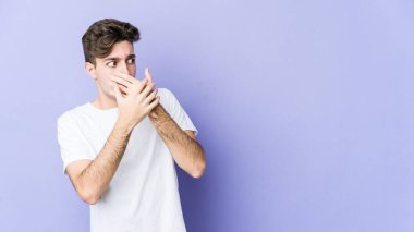 Mor arka planda izole edilmiş genç beyaz bir adam. Düşünceli bir şekilde ağzıyla ağzını kapatan bir fotokopi odasına bakıyor..