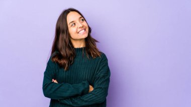 Genç, melez İspanyol kadın kendini soyutlamış, kollarını kavuşturarak gülümsüyor..