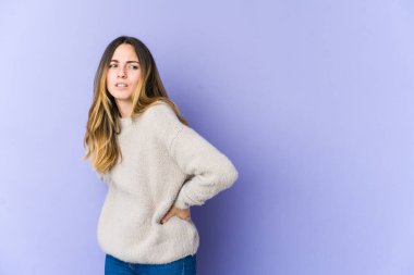 Mor arka planda izole edilmiş beyaz bir kadın sırt ağrısı çekiyor..