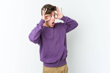 Beyaz arka planda izole edilmiş genç beyaz bir adam bir başarı fırsatı bulmak için gözlerini açık tutuyor..