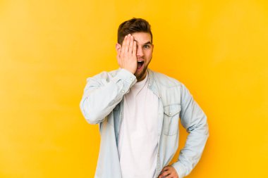 Sarı arka planda izole edilmiş genç beyaz adam yüzünün yarısını palmiye ile örterek eğleniyor..