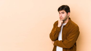 Bej arka planda izole edilmiş genç adam şüpheli, belirsiz, seni muayene ediyor..