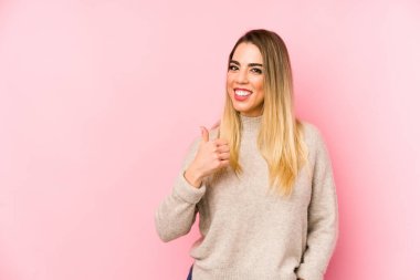 Orta yaşlı bir kadın soyutlanmış arka planda gülümsüyor ve parmağını kaldırıyor.