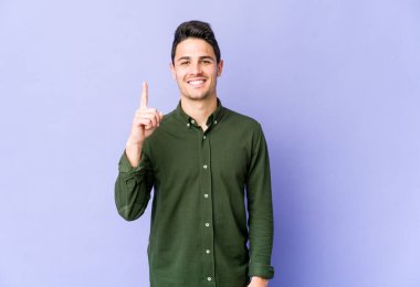 Mor arka planda izole genç beyaz adam parmak ile bir numara gösteriyor.