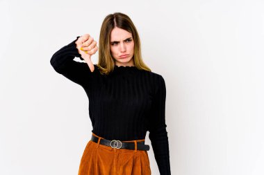 Beyaz arka planda izole edilmiş genç beyaz kadın baş parmağını aşağı gösteriyor ve hoşlanmadığını ifade ediyor..
