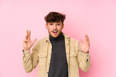 Arka planda poz veren genç Arap bir adam hoş bir sürprizle karşılaşıyor, heyecanlı ve el kaldırıyor..