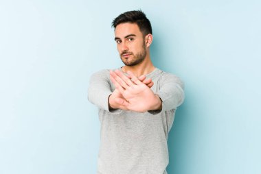 Mavi arka planda izole edilmiş genç beyaz adam elini uzatmış, dur işareti göstererek seni engelliyor..