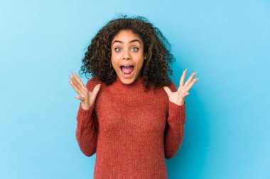 Genç Afro-Amerikan kıvırcık saçlı kadın zaferi ya da başarıyı kutluyor, şaşırdı ve şok oldu..