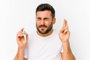 Termometre tutan genç beyaz bir adam şans dilemek için parmaklarını çapraz tutan beyaz bir adamı izole etti.