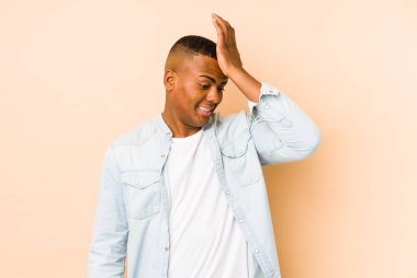 Genç latin adam bej arka planda izole edilmiş bir şekilde bir şeyi unutuyor. Alnına avuç içi ve kapalı gözlerle vuruyor..