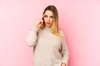 Soyutlanmış arka planda orta yaşlı bir kadın şakağı parmağıyla işaret ediyor, düşünüyor ve bir göreve odaklanıyor..