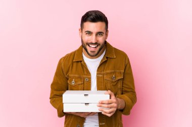 Pizzaları elinde tutan yakışıklı genç adam gülüyor ve eğleniyor..