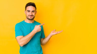 Kafkasyalı genç adam sarı fırında izole edilmiş. Elinde palmiye ağacının bir kopyası var..