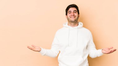 Bej arka planda izole edilmiş genç bir adam hoş bir ifade sergiliyor..