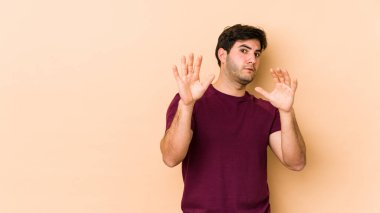 Bej arka planda izole genç bir adam yakın bir tehlike nedeniyle şoka uğruyor.