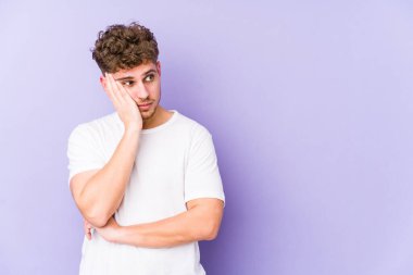 Genç, kıvırcık saçlı, yalnız, üzgün ve dalgın bir şekilde fotokopi odasına bakan beyaz bir adam..