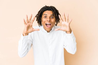 Genç Afrikalı Amerikalı Rasta adam hoş bir sürpriz alıyor, heyecanlı ve el kaldırıyor..