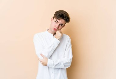 Beyazlı genç adam bej arka planda izole edilmiş. Tekrarlanan bir görevden yorulmuş..