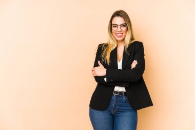 Orta yaşlı iş kadını bej arka planda izole edilmiş. Kollarını kavuşturup gülümsüyor..
