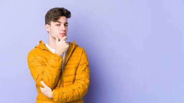 Mor arka planda izole edilmiş genç beyaz adam şüpheli, belirsiz, seni muayene ediyor..