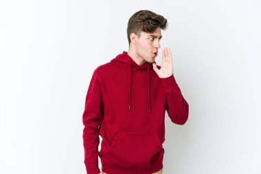 Beyaz arka planda izole edilmiş genç beyaz bir adam gizli bir sıcak fren haberi veriyor ve yana bakıyor.