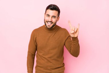 Pembe arka planı olan genç beyaz bir adam boynuzlarını devrim konsepti olarak gösteriyor..